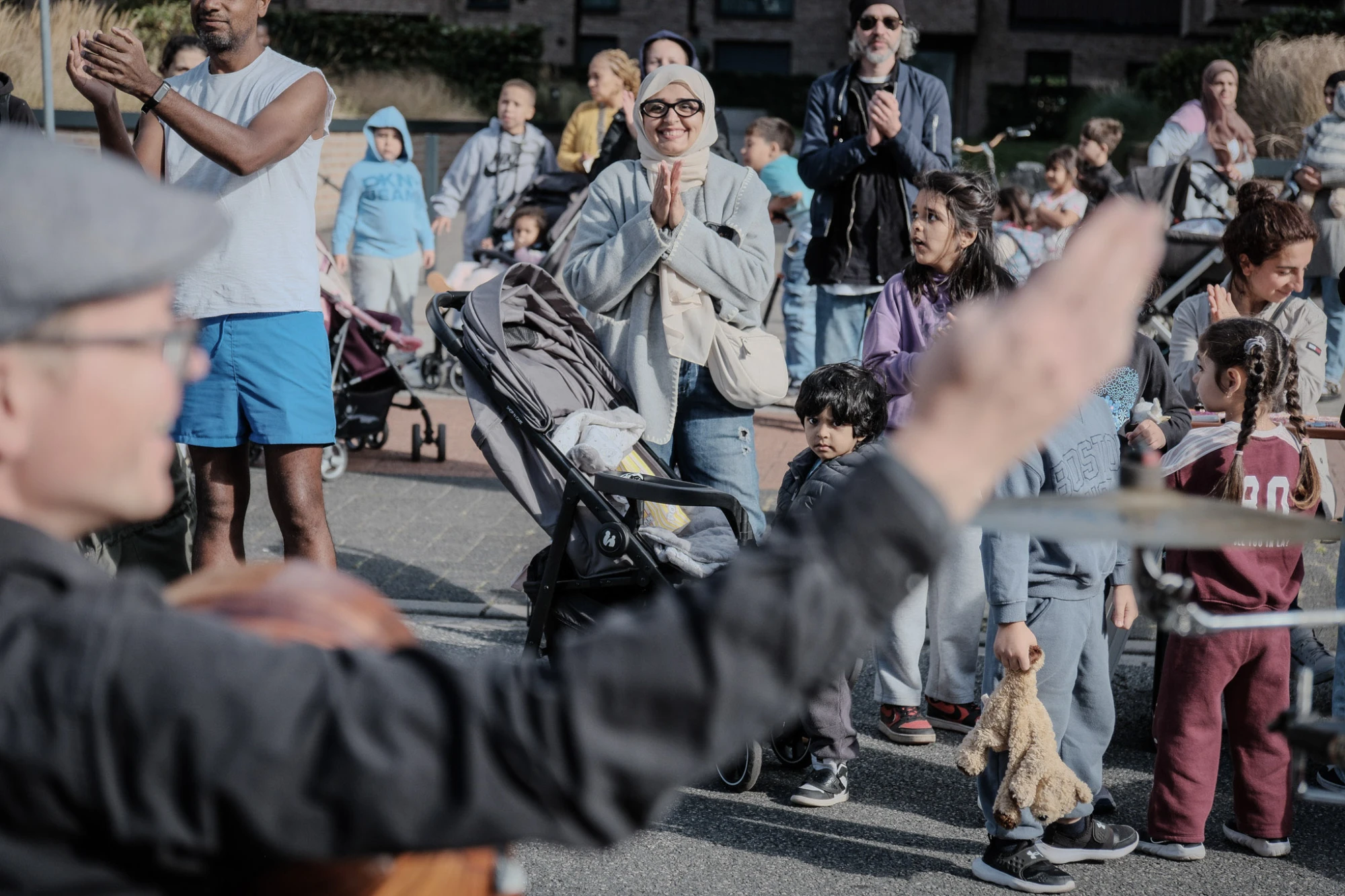 Menschen unterschiedlichen Alters klatschen und schauen auf eine Person im Vordergrund, die mit ausgestreckten Armen spielt oder dirigiert