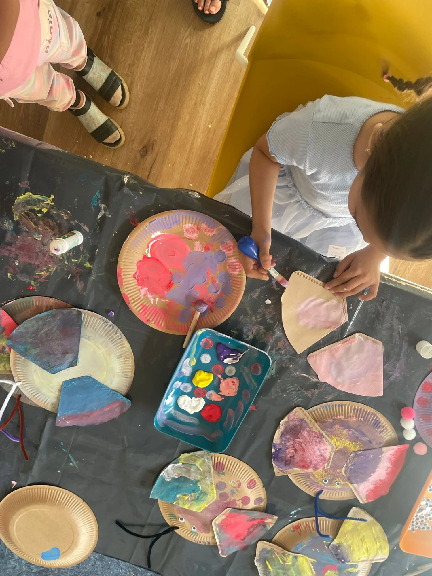 Das Foto zeigt ein M&auml;dchen, das aus einem Pappteller einen bunten Schmetterling gestaltet.